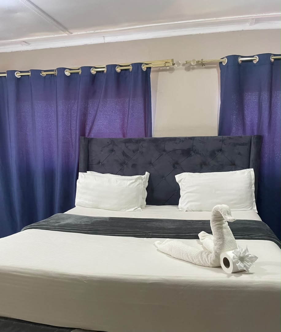Double room with a navy headboard, blue curtains and a towel swan on the bed