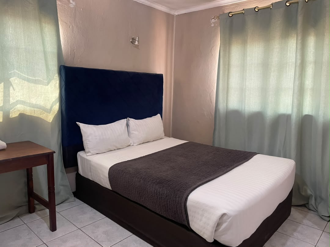 Double room with a navy headboard, white linen and sage green curtains