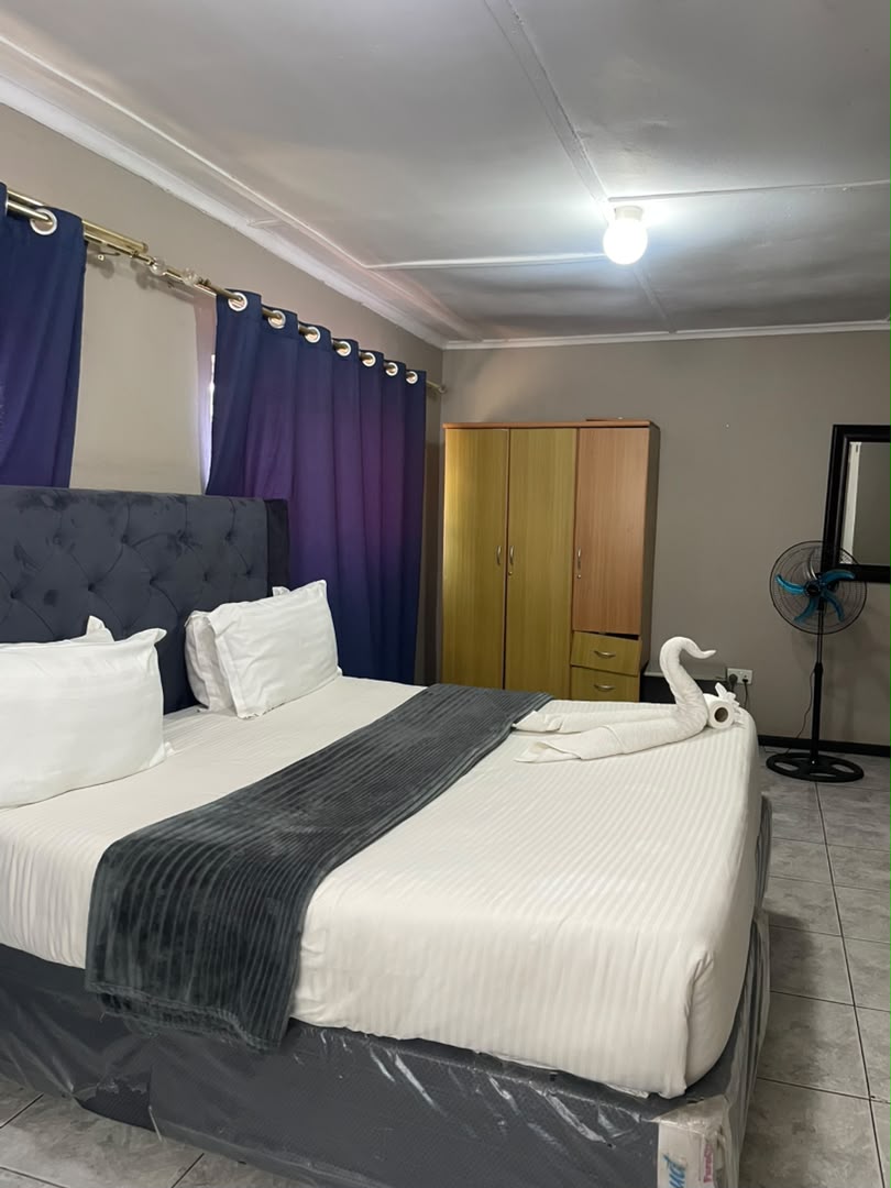 Spacious room with a large bed, wardrobe, mirror and standing fan